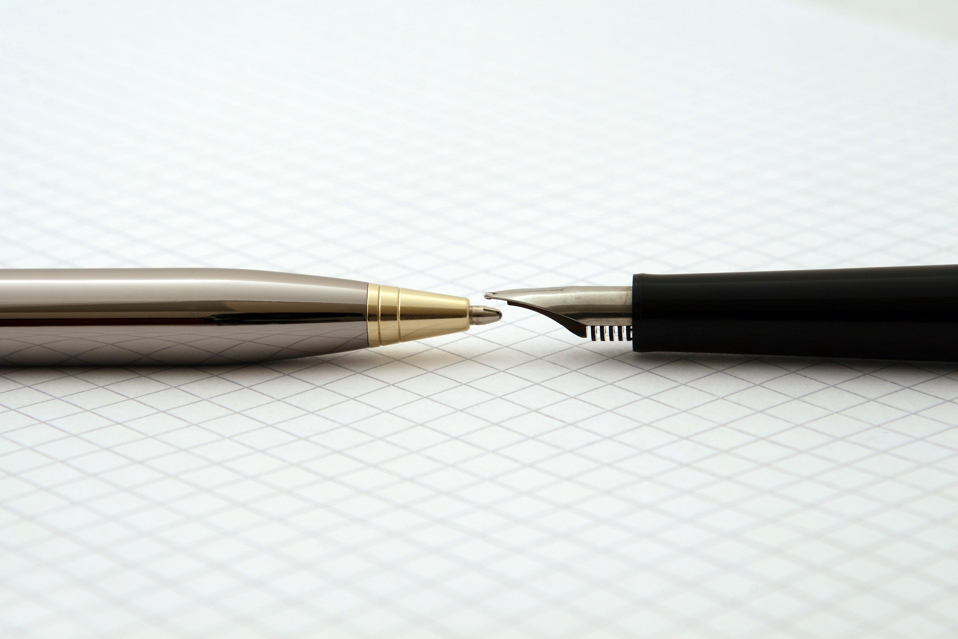 Deux stylos sont posés sur une feuille quadrillée, mines placées l'une en face de l'autre.