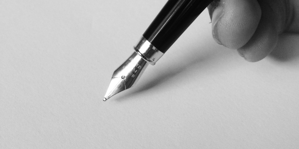 Une main écrit au stylo plume.